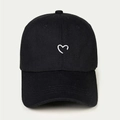 Detail of a black cotton baseball cap featuring a small white embroidered heart on the front - Adjustable / Black