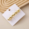 Detail view of a gold star hair clip with five continuous stars on a white display card - Hammered Star Chain Gold