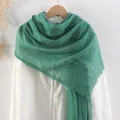Deep green cotton linen scarf with frayed edges hanging on a white shirt with a wooden hanger - Green