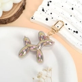 Rainbow balloon dog keychain with golden metallic ring on a textured tray - Iridescent Khaki