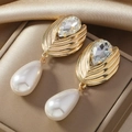 Orecchini pendenti in oro con cristalli e perle su sfondo di raso champagne - Oro