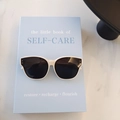Retro cat-eye children sunglasses with white frame and dark lenses on a book - Off White
