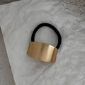 Elegant gold bow-shaped metal hair tie with black elastic band on textured white background - Arc Ponytail Cuff / Gold