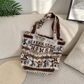 Detail van pluche draagtas met sneeuwvlokpatroon en bruin lederen merklabel - Pluche Tarwe-aren