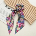 Detailweergave van een zijden haarelastiek met bloemenmotief en lange linten op hout - Tie-Dye Bloemenpatroon