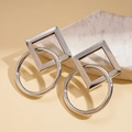 Macro shot of silver geometric square and circle stud earrings on a natural stone base - Silver
