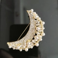 Detailed close-up of crescent moon brooch with sparkling rhinestones and white pearls - Moon