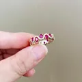 Macro-opname van een golvende rij ovale rode edelstenen en zirkonen in een gouden ring - Rood (Goudkleur)