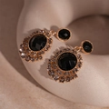 Detalle de pendientes vintage dorados con piedras negras facetadas y cristales grises - Girasol Redondo Negro (Pin de Plata)
