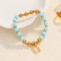Minimalist sky blue and gold bead bracelet with a hollow bear charm on white tray - Sky Blue Beads-Gold Hollow Bear Charm