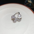 Detail eines silbernen Schleifenrings mit weißen Perlen und Zirkonia auf Keramik - Einstellbar Offen / Silber