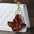 Portachiavi a fiore di camelia in pelle marrone con chiusura dorata su borsa bianca - Marrone