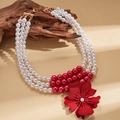 Detailed close-up of a three-layer pearl necklace with a large red flower pendant on wood - Triple Layer Pearl Necklace / Red