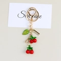 Macro shot of cherry keychain with handmade metal tag and red fruit charms on card - Cherry Pendant