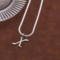 Minimalist silver letter X pendant with snake bone chain on dark leather texture - Letter X