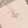 Gros plan du collier papillon doré avec ailes violettes sur un support en pierre - Violet