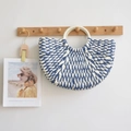Detail of blue and white semicircular woven handbag with circular handles on a wall hook - Blue and White Contrast