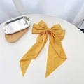 Close-up of a yellow ribbon bow hair clip with fabric texture on a wooden tray - Bright Yellow