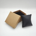 Detail view of square kraft paper gift box with a soft black leather watch cushion inside - Beige Kraft Paper