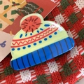 Detailed view of festive knitted hat brooch on Christmas themed background fabric - Knit Hat Claw Clip-6.4cm