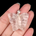 Pink natural quartz crystal butterfly pendant with silver bail shown in hand - White Crystal