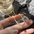 Detail view of a sparkling silver chain necklace with a green round gemstone pendant - Emerald Green Rhinestone Necklace