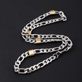 Macro view of silver stainless steel Figaro necklace with gold bead accents on black background - 8mm Figaro Chain With Gold Beads Necklace