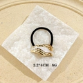 Macro shot of wavy gold hair cuff with white enamel detail and black elastic band - White Enamel