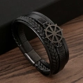 Détail du bracelet multicouche en cuir noir avec breloque gouvernail sur bois sombre - Noir + Noir Mat
