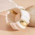 Detail of chunky acrylic cuff bracelet with gold metal accents and elastic band - White