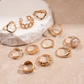 Dettaglio set di 10 anelli geometrici dorati su marmo con diverse finiture materiche - Oro