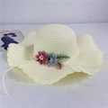 Close-up of beige straw sun hat with wavy brim and colorful floral decorations - Adult M (56-58cm) / Creamy White