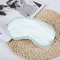 Mint green faux silk sleep eye mask with elastic strap on a rustic woven mat - Cream Green
