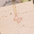 Dettaglio di una collana dorata con ciondolo a farfalla rosa e piccolo zircone bianco - Rosa