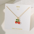 Detailed view of a gold-tone chain necklace featuring a sweet red strawberry-shaped pendant - Double Strawberry Necklace Gold