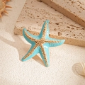 Detail eines blauen Seestern-Rings mit Goldakzenten auf sandsteinartigem Hintergrund - Blauer Seestern-Stil