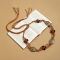 Detail of bohemian woven waist chain with turquoise stones and beads on a vintage book - Brown Macrame Turquoise Bronze Disc (X502-15)