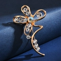 Elegant gold flower brooch with radiant rhinestones and pearls on a textured background - Iridescent Flower