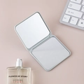 Miroir de poche carré gris pliable avec double face en verre sur un bureau rose - Bleu clair