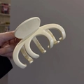 Dettaglio ravvicinato della grande molletta per capelli color crema con finitura lucida in mano - Bianco Sporco