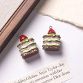 Macro shot of two realistic strawberry chocolate cake pendants with layered cream details - Dark Brown + White Filling