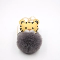 Close-up of cute cartoon tiger faux fur ball keychain with gold metal ring and spring clasp - Gold Keychain / Dark Gray