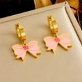 Golden hoop earrings with pink enamel bow pendants on a beige jewelry display pad - Pink Bow Earrings (E6175)