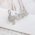 Elegant silver musical note brooch with sparkling rhinestones on white fabric - Silver Music Note
