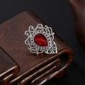 Vintage palace style brooch featuring a pear-cut red gemstone and ornate silver filigree - Retro Red Gemstone Style (0308)