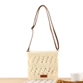 Minimalist beige woven straw crossbody bag with brown leather strap on wooden surface - Cream