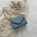 Light blue quilted crossbody bag with stylish pearl strap on beige blazer - Blue