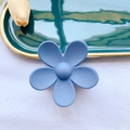 Detailed macro view of the matte pastel blue flower hair claw clip on a luxury tray - Blue
