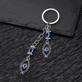 Detail of vintage Fatima Hand keychain with blue evil eye beads on black stone background - Double Eye Pendant
