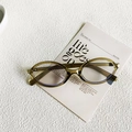 Chic oval olive green sunglasses with blue light lenses on a minimalist white card - Transparent Green White Lens